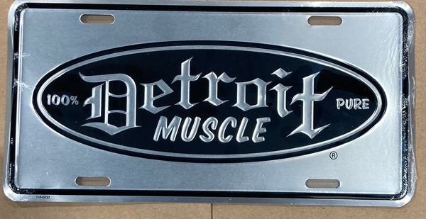 A silver embossed metal license plate with the text 'DETROIT MUSCLE' and '100% PURE' on it.
